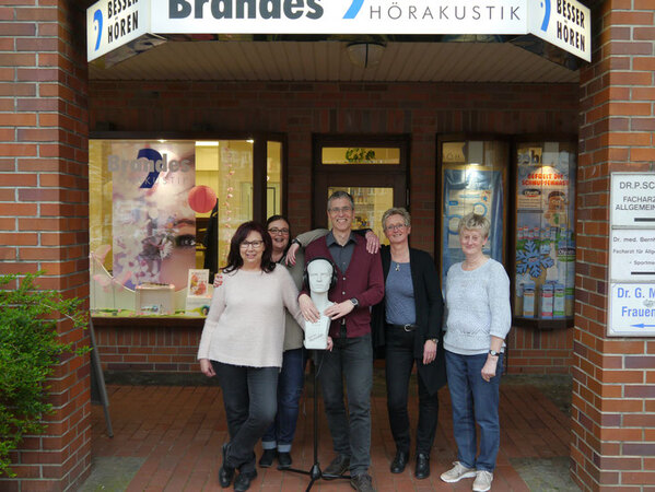 Fünf Personen stehen lächelnd vor dem Hörakustik-Fachgeschäft Brandes in der Innenstadt.